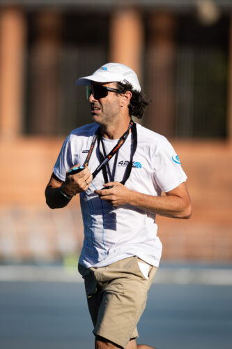 Entrenador de atletismo supervisando una sesión de entrenamiento de corredores.